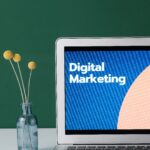About A laptop displaying 'Digital Marketing' with a minimalist floral decor in a glass vase.